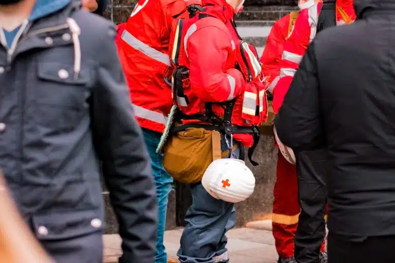A red cross worker with a hardhat branded with the Red Cross Logo