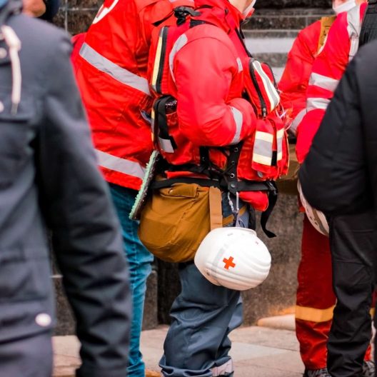 A red cross worker with a hardhat branded with the Red Cross Logo